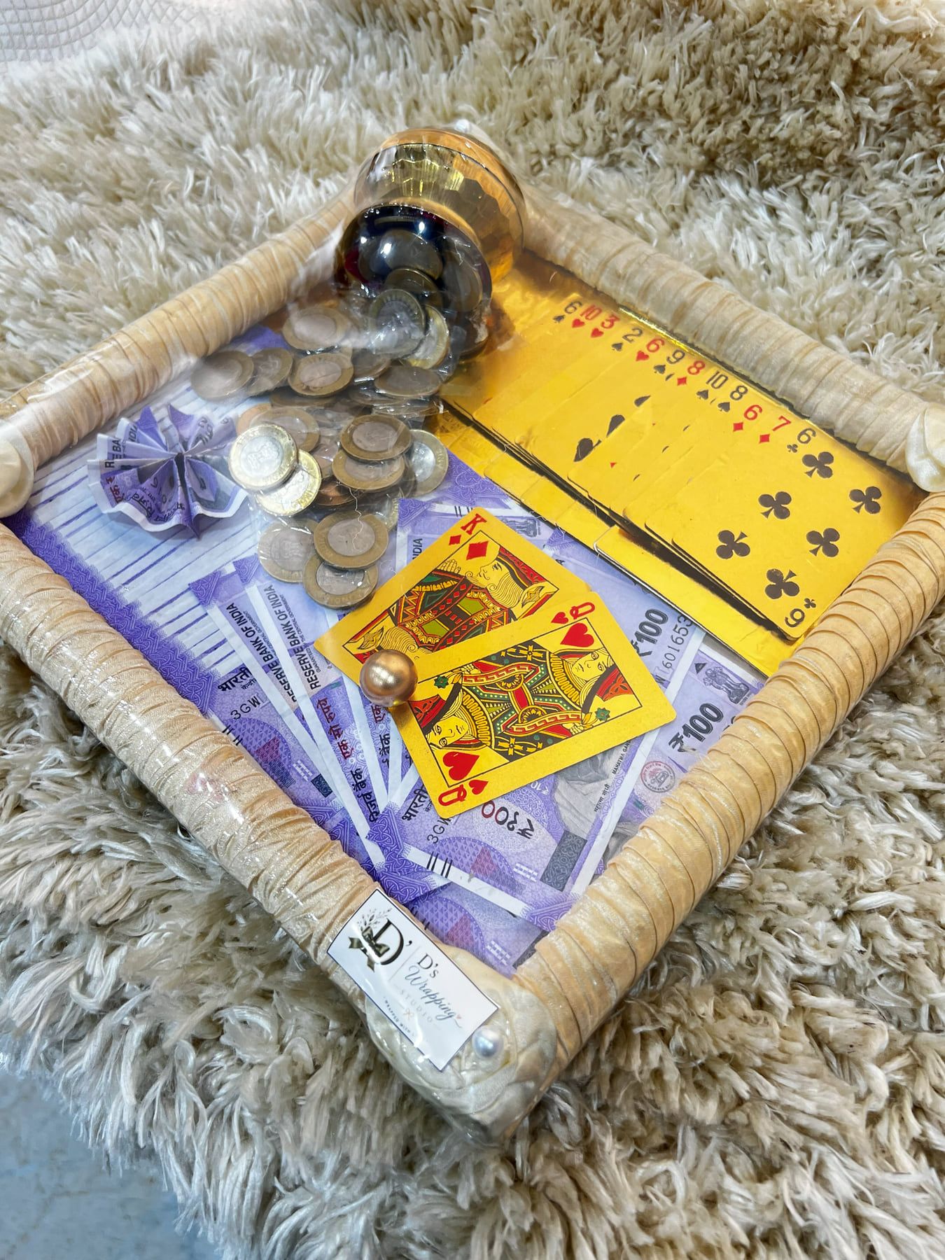 Rattan tray with a jar of coins, yellow playing cards and currency notes