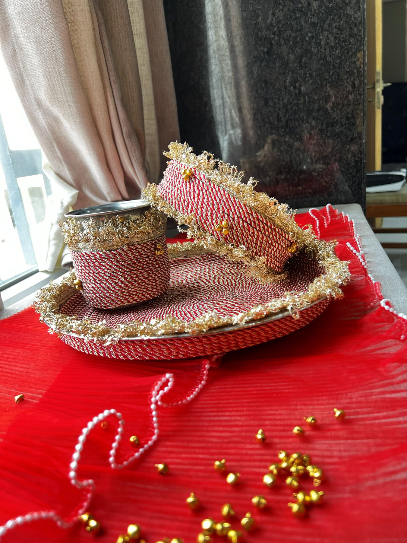 Red and gold decorated Karwa Chauth thali with matching karwa and chalni on red fabric